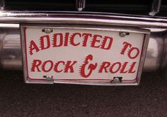 a red and white sign on the side of a car that says, adicted to rock & roll