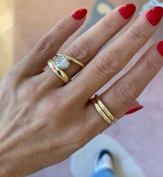 a woman's hand with red nails and two gold rings on her left hand