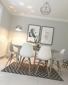 a dining room table with four chairs and two pictures on the wall in front of it