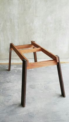 a wooden table sitting on top of cement floor next to a concrete wall with no one around it