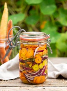 a jar filled with sliced vegetables sitting on top of a wooden table