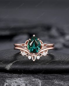 a ring with a green stone in the center on top of a black rock,