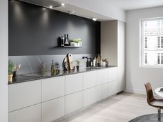 a kitchen with gray cabinets and white counter tops is pictured in this image, there are plants on the counters