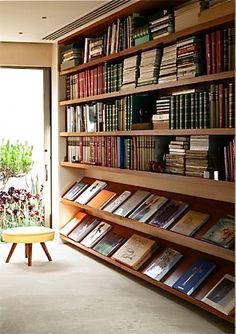 a bookshelf filled with lots of books next to a window