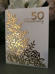 a 50th anniversary card with gold foil flowers and the number 50 on it's front