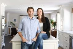 a man and woman are standing in the middle of a kitchen with white countertops