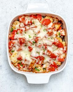 a casserole dish with tomatoes and cheese in it on a white counter top