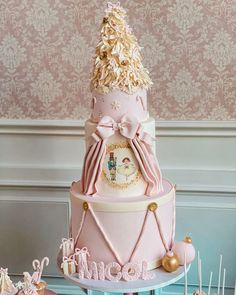 a pink and white cake with gold decorations on it's top, sitting on a table