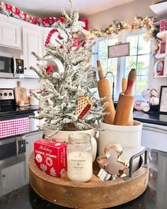 a christmas tree in a kitchen decorated with red and white ornaments, candles, jars and other holiday decor