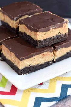 three pieces of chocolate peanut butter bars on a plate with a colorful towel in the background