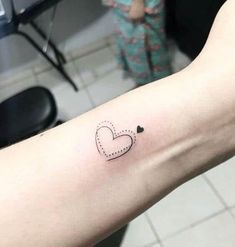 a small heart tattoo on the left inner arm, with an arrow in the middle