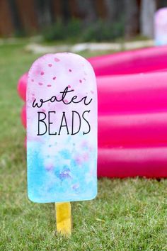 an ice lolly popsicle sitting in the grass with water beads written on it