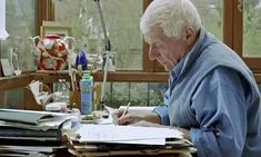 an older man sitting at a desk writing on a piece of paper