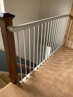 a stair rail in a house with carpet on the ground and walls behind it,