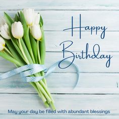 a bouquet of white tulips sitting on top of a wooden table next to a blue ribbon