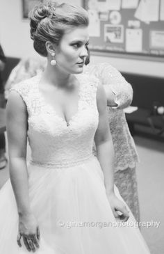 a black and white photo of a woman in a wedding dress looking at the camera