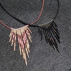 two necklaces that have been made with beads and some black string on them, sitting on top of a table