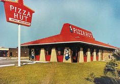 a large pizza hut sitting on top of a lush green field