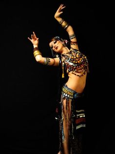 a woman in belly dance clothing and headdress is doing an acrobatic move