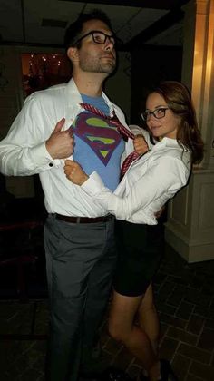 a man and woman are dressed up in business attire, one is holding a superman t - shirt