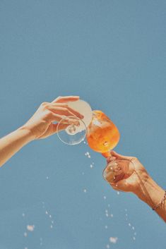 two people toasting with wine glasses against a blue sky