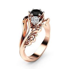 a rose gold engagement ring with an oval black diamond in the center and leaves on the side