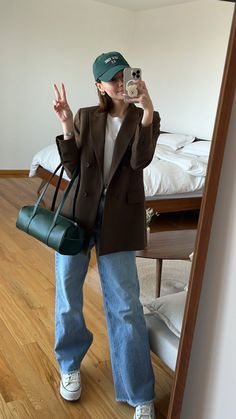 a woman taking a selfie in front of a mirror while holding a green purse