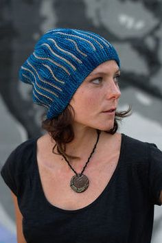 a woman wearing a blue knitted hat with a medallion on it's neck