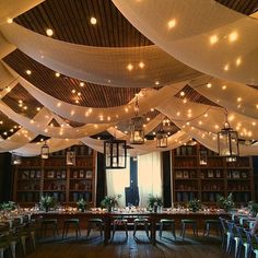 a dining room with lots of lights hanging from the ceiling and tables set for dinner