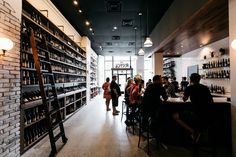 people are sitting at tables in a wine store with shelves full of bottles and glasses