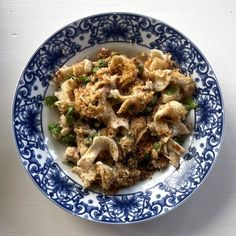 a blue and white bowl filled with food on top of a table next to a wall