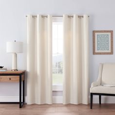 a living room with white curtains and a chair