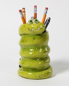 a stack of green stuff with pencils sticking out of it's eyes and smiling faces