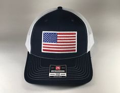 American Flag 6 Panel Adjustable Snapback Trucker Mesh Hat Richardson 112, US Flag Hat, American Flag Hat, Richardson 112 Embroidered American Flag Heat Sealed Patch Richardson 112 Hat Details:    -60/40 cotton/polyester    -100% polyester mesh back    -Structured, six-panel, mid-profile    -Pre-curved contrast stitched visor    -Underbill matches the color of the visor    -Adjustable plastic snapback Hat will be shipped in a box for protection. Patriotic White Trucker Hat With Curved Brim, White Patriotic Hat With Curved Brim, Adjustable Patriotic Hat With Flat Bill, White Patriotic Baseball Cap With Flat Bill, White Patriotic Flat Bill Baseball Cap, White Patriotic Snapback Hat With Flat Bill, Adjustable Patriotic Hats For Sports Events, Adjustable Patriotic Hat For Sports Events, American Style Hat With Curved Brim And American Flag