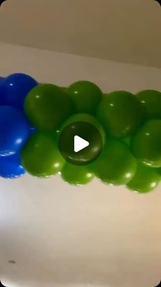 the balloons are green, blue and white in this room with a video playing on it