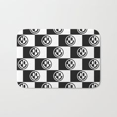 a black and white checkered bath mat with smiley faces on the front, in different colors