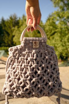 a hand holding a purse made out of knitted material, with a wooden handle