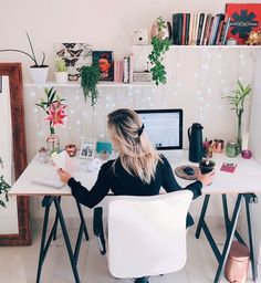 a woman sitting at a desk in front of a computer and holding a coffee cup