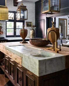 a kitchen with an old fashioned sink and marble counter top in front of large windows