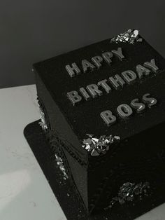 a black birthday cake with silver foil on it's edges and the words happy birthday boss