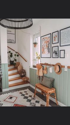 a room with some pictures on the wall and a chair in front of it next to a stair case