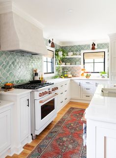 a kitchen with white cabinets and an area rug on the floor in front of the stove