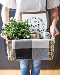 a person holding a basket with plants in it and a sign that says home sweet home