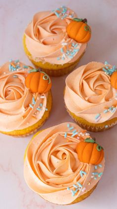 four cupcakes with frosting and pumpkin decorations