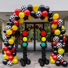 a large balloon arch decorated with black, red, yellow and white checkered balloons