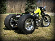 a yellow motorcycle parked on top of a grass covered field with trees in the background