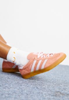 a woman's feet wearing pink adidas sneakers with white socks and orange soles