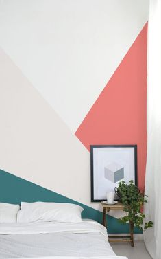 a white bed sitting in a bedroom next to a wall painted with different colors and shapes