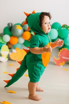 a toddler in a green dinosaur costume