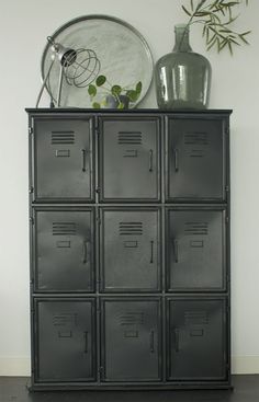 a black cabinet with many drawers next to a vase